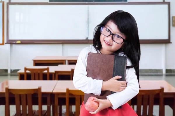 Enfant tient un livre et une pomme en classe — Photo