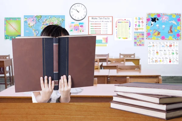 Kind lezen boeken en haar gezicht bedekken — Stockfoto