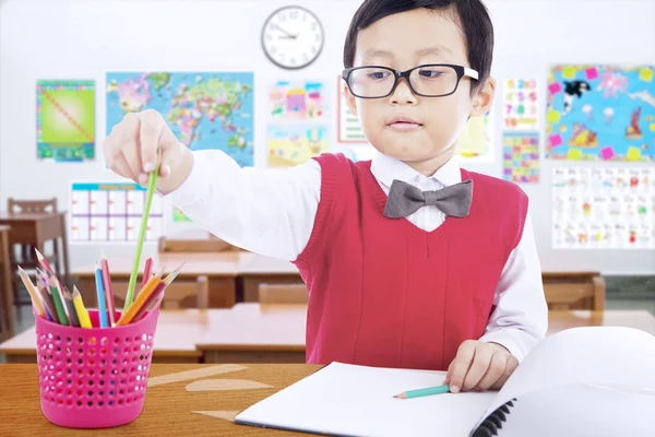 Child using crayon to draw in the class — Stock Photo, Image