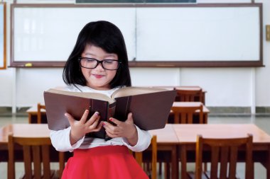 Little learner reading a book in class