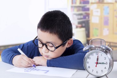 Little schoolboy drawing in the classroom