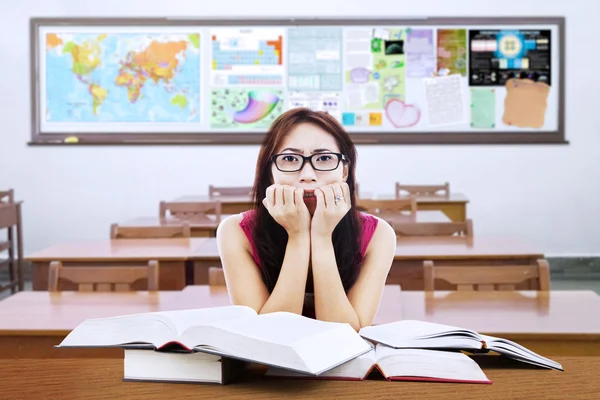 Zdezorientowany student brunetka z książek w klasie — Zdjęcie stockowe