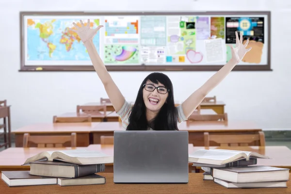 Захоплена жінка-вчителька піднімає руки в класі — стокове фото