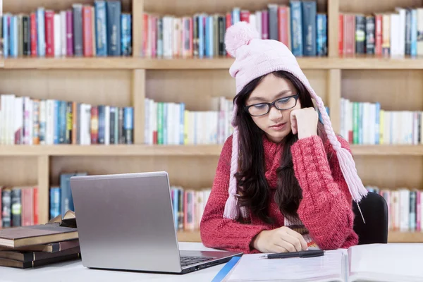 Girl studying in library while wearing sweater — Stockfoto