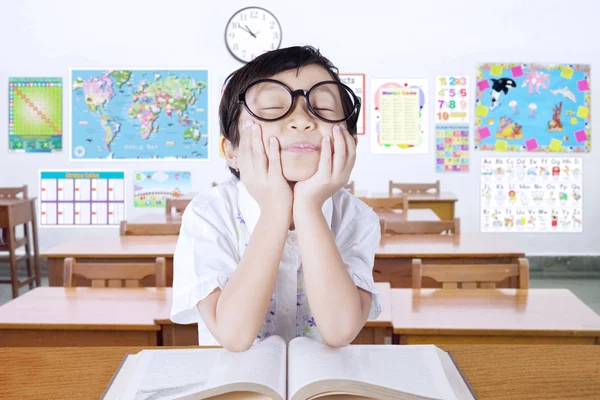 Nachdenkliches kleines Mädchen mit Buch im Klassenzimmer — Stockfoto