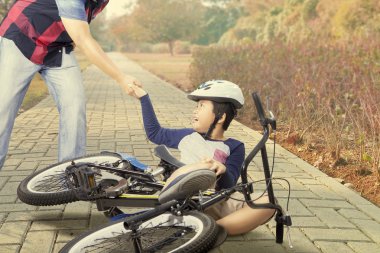 Child gets crash with bike and helped by dad clipart