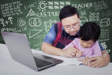 Erkek öğretmen öğrencisini yazmak için yardımcı olur.