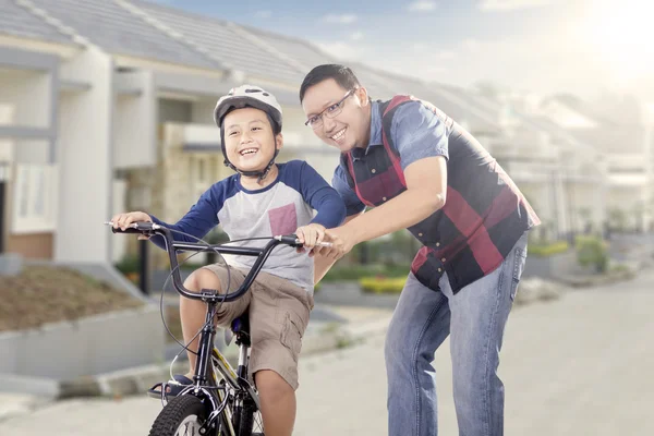 Dad teaching his son to ride a bike