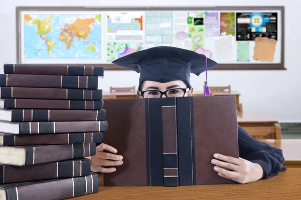 Graduate student cover her face with book — Stock Photo, Image