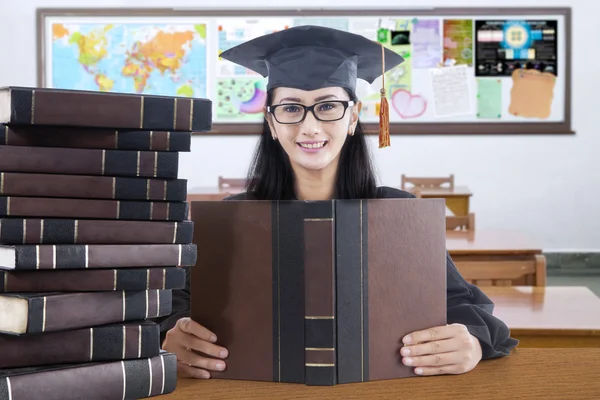 Graduate student with mortarboard studying in class — Stock Photo, Image