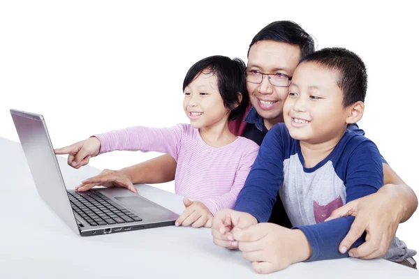 Děti pomocí přenosného počítače na stole s otcem — Stock fotografie