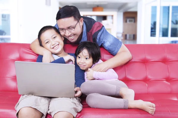 Bambini adorabili con papà che usano il computer portatile sul divano — Foto Stock