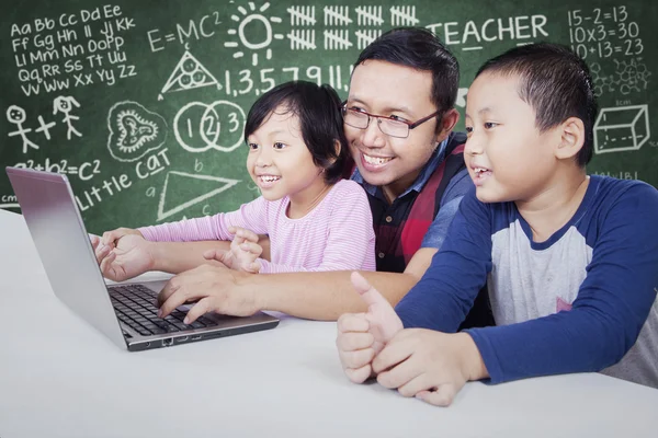 Professor do sexo masculino ensinar dois alunos com laptop — Fotografia de Stock