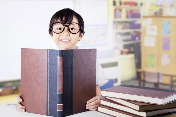 Süßes kleines Mädchen mit Büchern in der Klasse — Stockfoto
