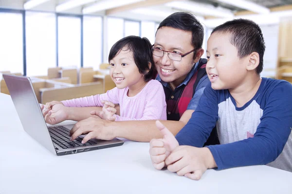 Dos estudiantes usando laptop en clase con el profesor — Foto de Stock