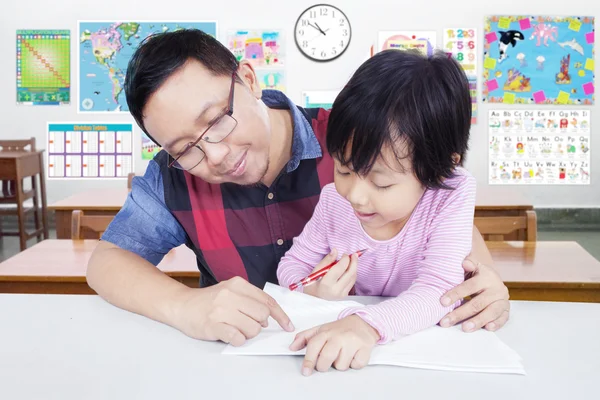 Young teacher helps student to write — Stock Photo, Image