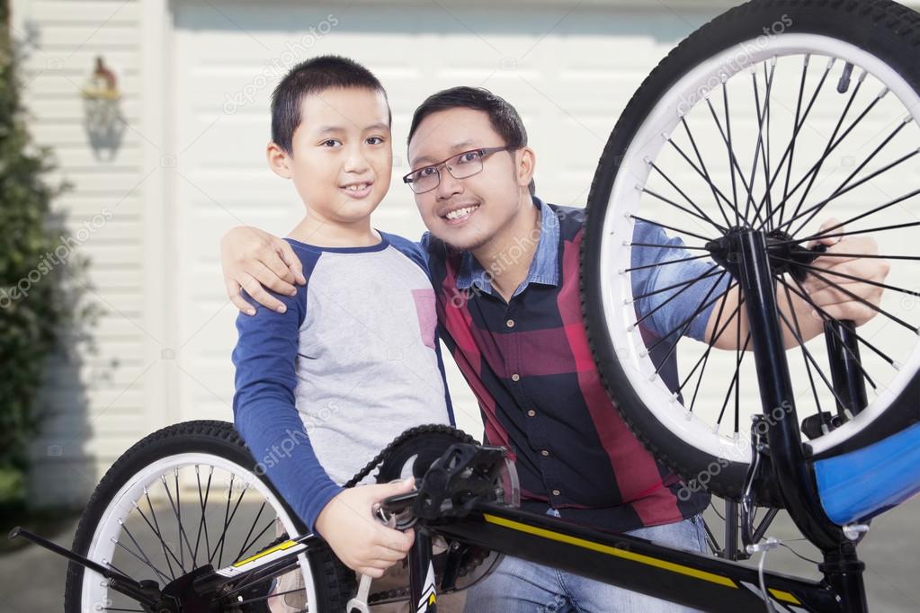 Cute boy and his father repairing bicycle