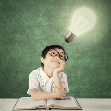 Adorable little student looking at light bulb