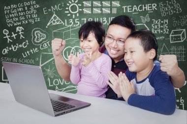 Cheerful students clapping hands in class with teacher
