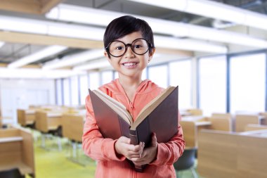 Cute child reading literature in the classroom