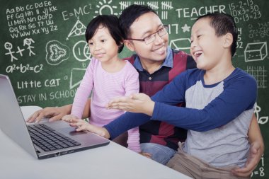 Student showing laptop on his friend and teacher