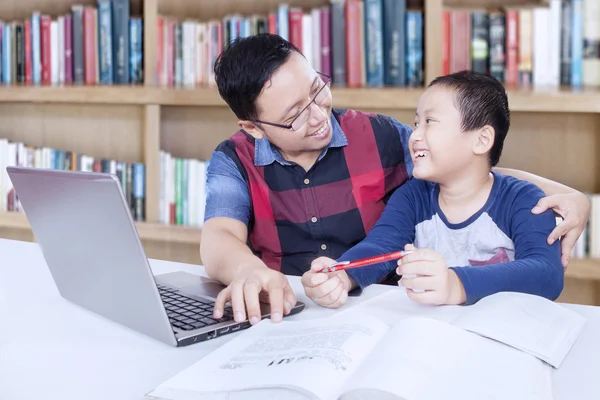 Boy talking with his teacher in library — Stockfoto