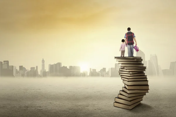 Child and her dad standing on a pile of books — Zdjęcie stockowe