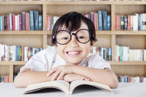 Criança mostrando um sorriso de dente na biblioteca — Fotografia de Stock