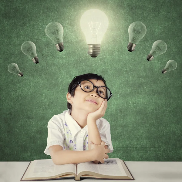 Child thinks inspiration under bright light bulb — Stok fotoğraf