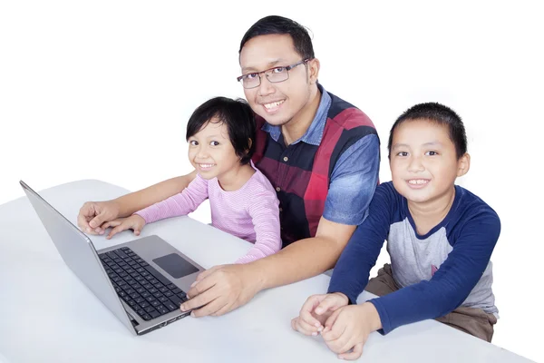 Niños y papá sonriendo mientras usa el portátil —  Fotos de Stock