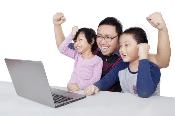 Children and dad using laptop while raising hands — Stockfoto