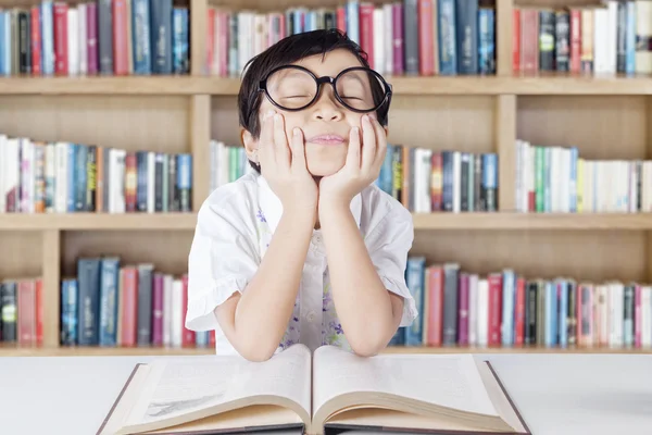 Süße Studentin mit Brille tagträumt in Bibliothek — Stockfoto