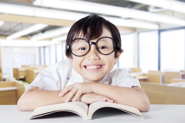 Female kid smiling at the camera while reading book — Φωτογραφία Αρχείου