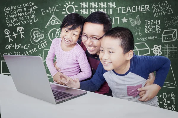 Bambini e insegnante si divertono con il computer portatile in classe — Foto Stock