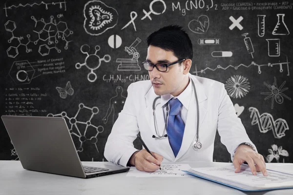 Male doctor writes medical reports — Stock Photo, Image