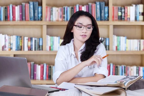 Estudante inteligente aprende com livros na biblioteca — Fotografia de Stock