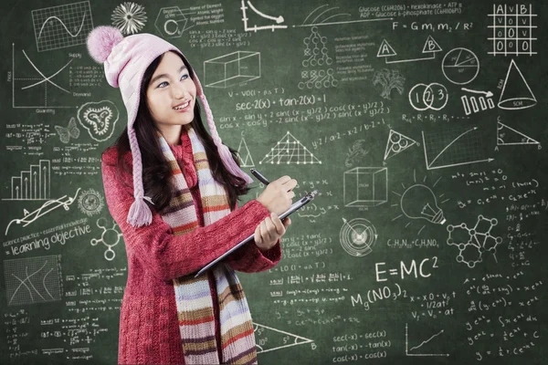 Student in sweater writes on lipboard at class — Zdjęcie stockowe