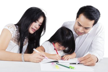 Child write on the book with her parents