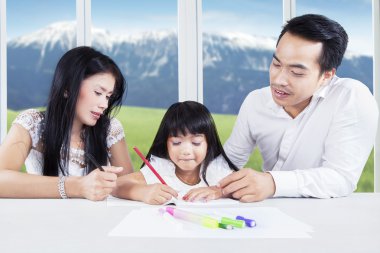 Clever child doing school task with parents