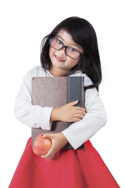Adorable little girl holds a book and apple in studio — Stock fotografie