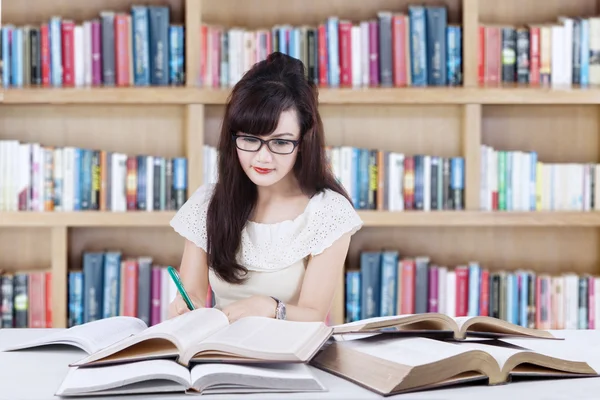 Attactive learner doing school task in library — Stock fotografie