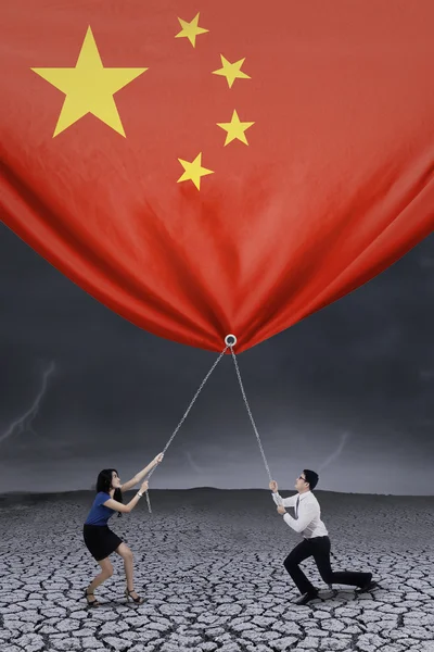 Businesspeople pulling down a chinese flag — Φωτογραφία Αρχείου
