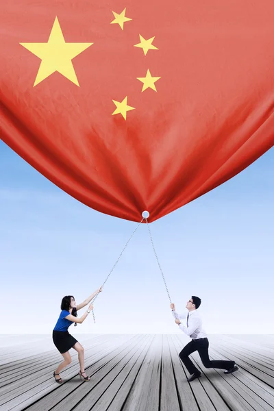 Entrepreneurs pulling down a chinese flag — Φωτογραφία Αρχείου