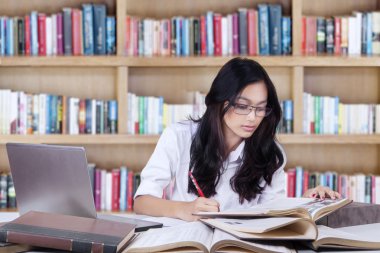 Güzel öğrenci Kitaplığı'nda okul ödevi yapıyor