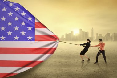 Two businesspeople pulling an american flag