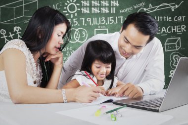 Two parents teach their child in the class