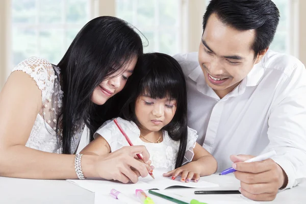 Friendly parents help their kid wrote on the book — Stockfoto