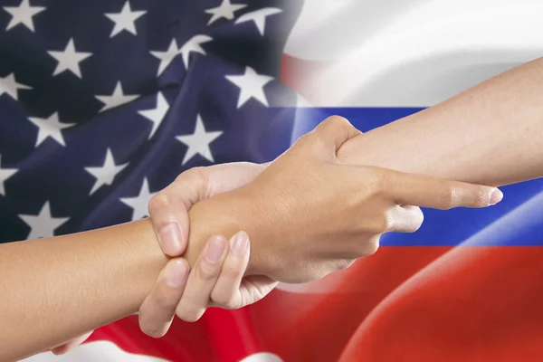 Helfende Hände mit amerikanischen und russischen Flaggen — Stockfoto