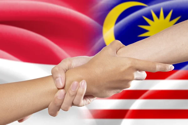 Helping hands with indonesian and malaysian flags — Stock Photo, Image