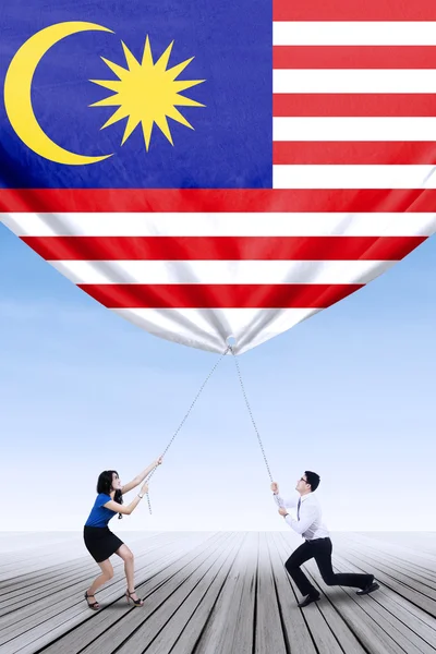 Mann und seine Partnerin reißen malaysische Flagge herunter — Stockfoto